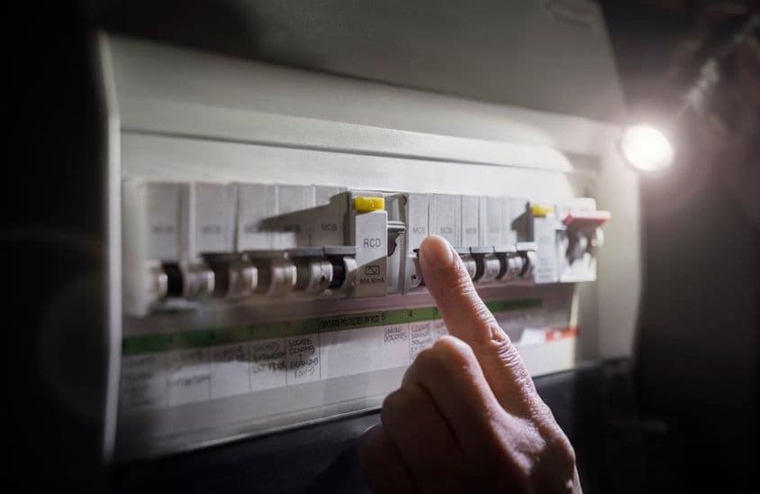 Áramkimaradás vészhelyzeti be- vagy kikapcsoló áramkör-megszakító elektromos biztosítéktáblán zseblámpával.