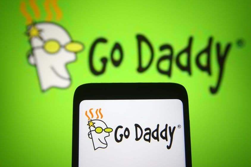 GoDaddy Inc logója látható egy mobiltelefonon és egy számítógép képernyőjén.