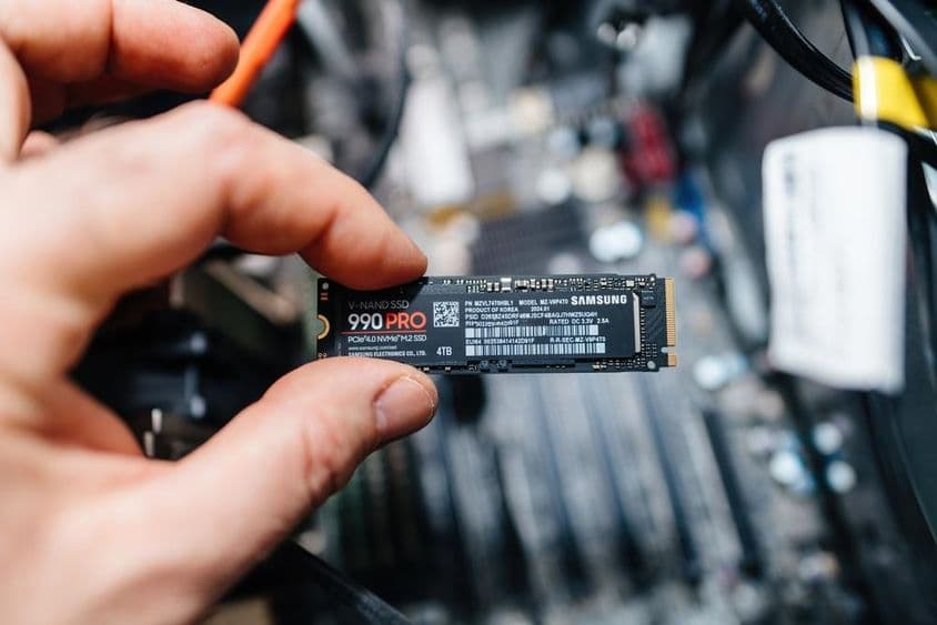 Egy férfi kéz egy Samsung 990 Pro NVMe ultragyors merevlemezt tart.