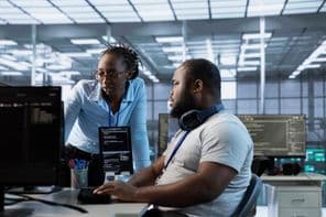 Egy technikus, aki a kezelő segítségét kéri, miközben az adatközpontban a számítógépen dolgozik.